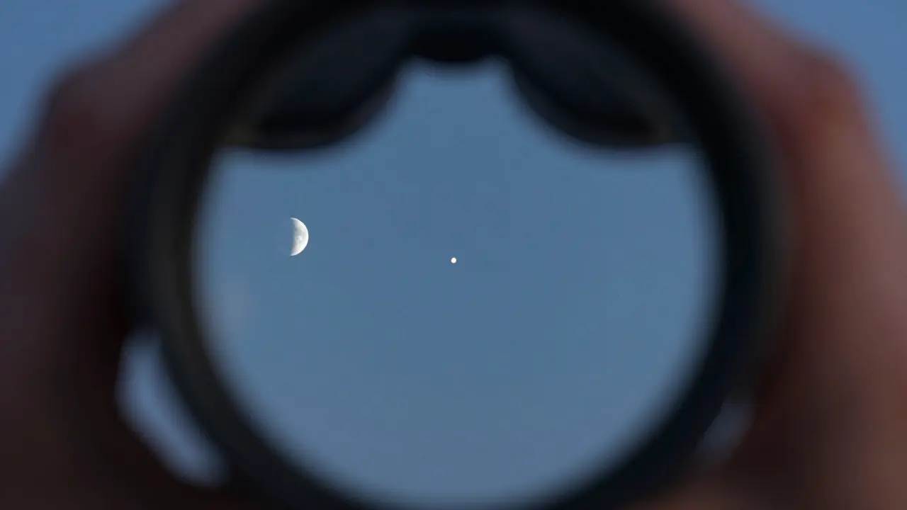 View through binoculars showing Mercury and the crescent Moon